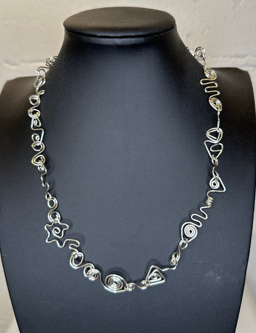 Silver necklace on a black mannequin against a white background