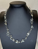 Silver necklace on a black mannequin against a white background