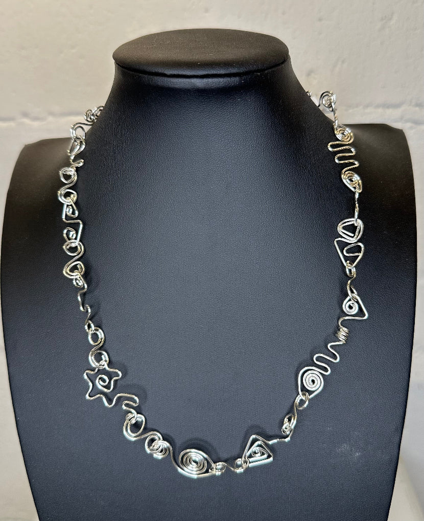 Silver necklace on a black mannequin against a white background