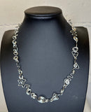 Silver necklace on a black mannequin against a white background