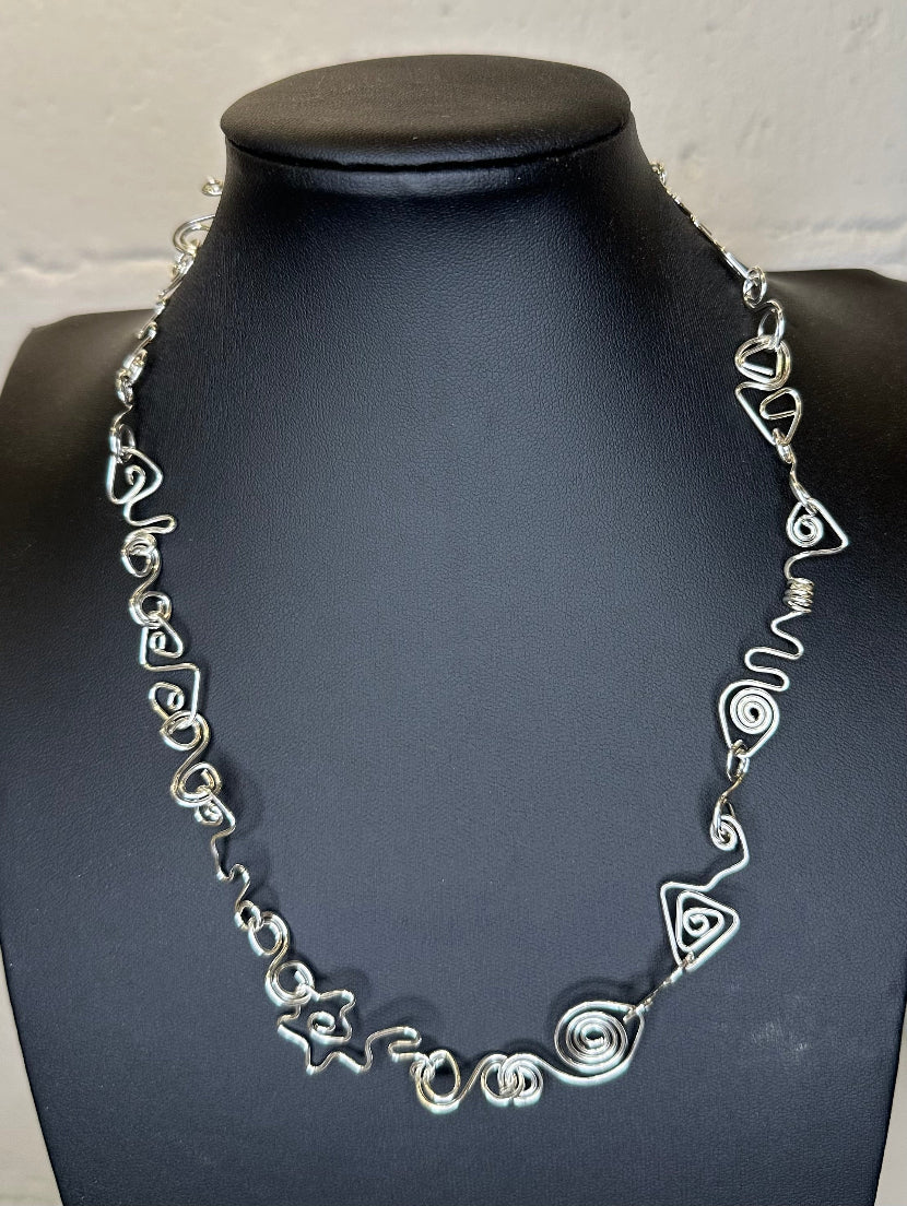 Silver necklace on a black mannequin against a white background
