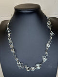 Silver necklace on a black mannequin against a white background