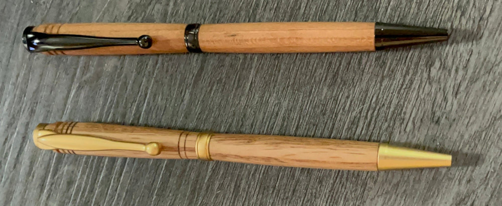 Two wooden pens with black and gold accents on a gray surface