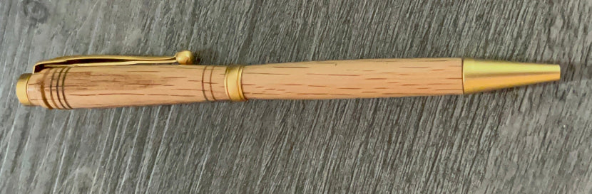 Wooden pen with gold accents on a wooden surface