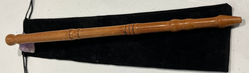 Wooden wand with a black pouch on a white surface